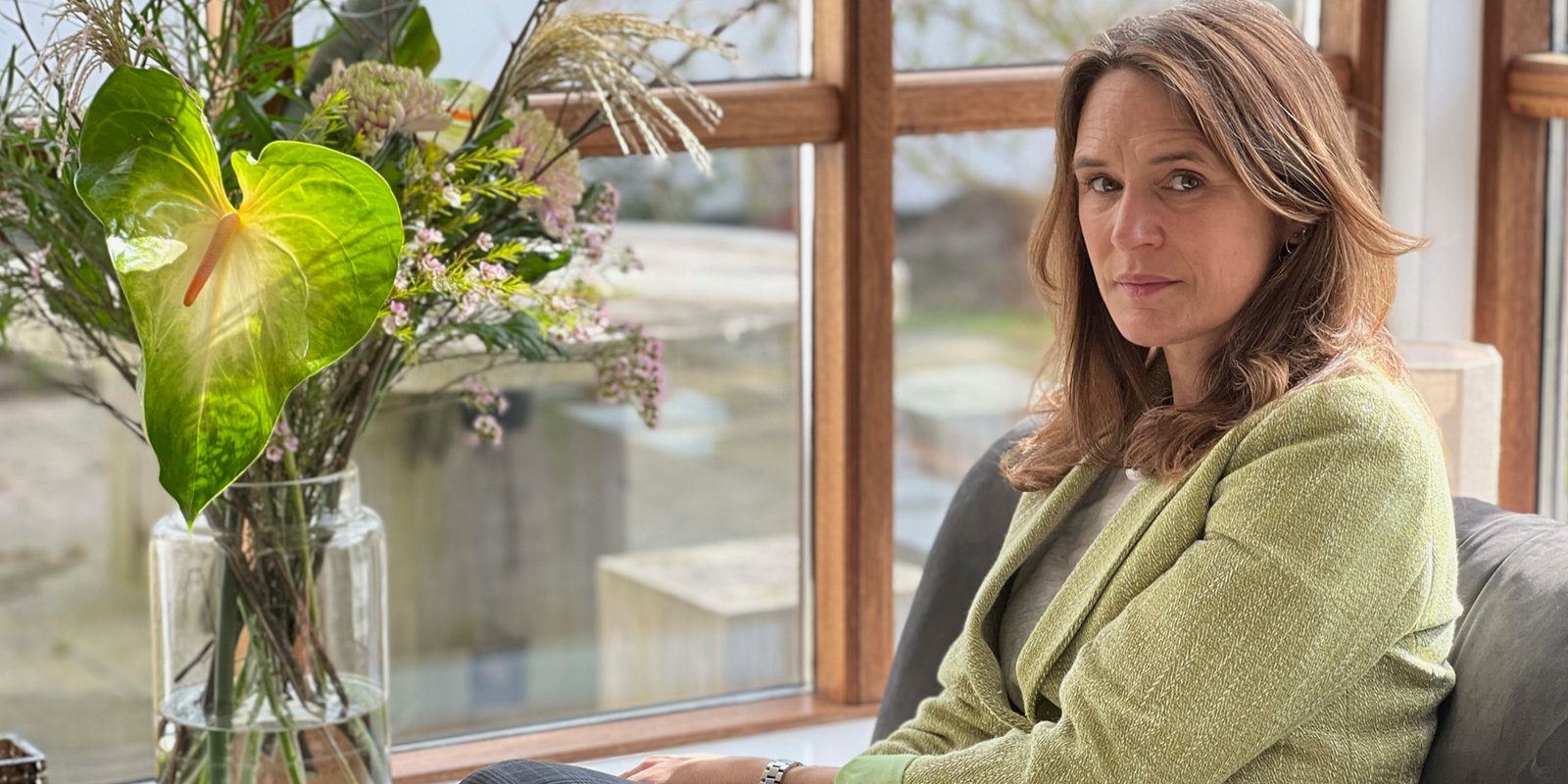 Franciska Valstorp Cortsen ved vinduet med blomster i eftermiddagslys
